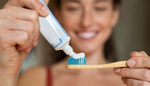 donna con spazzolino da denti e dentifricio